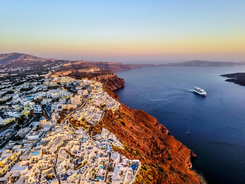 pexels-photo-1518498-1518498-1 Stunning aerial shot of Santorini coast at sunset with a cruise ship in the Aegean Sea.