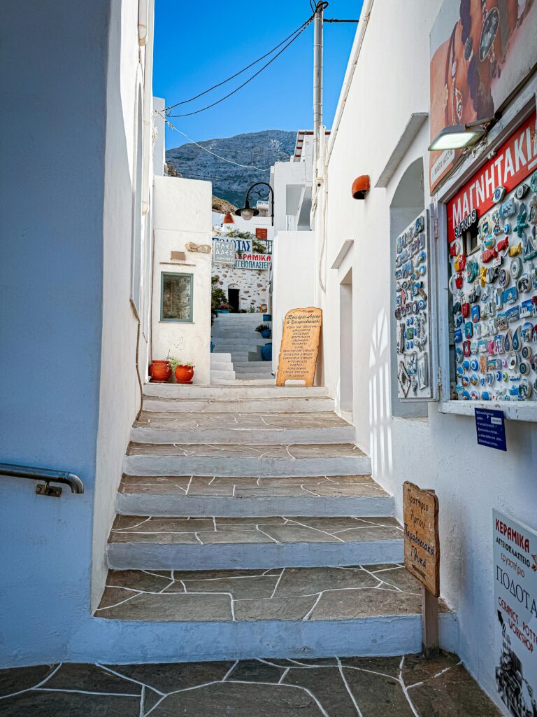 pexels-photo-27455018-27455018 Explore a quaint alleyway in a Greek island town with whitewashed buildings and blue accents.
